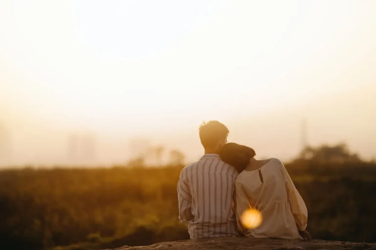 a man and woman sitting on a rock